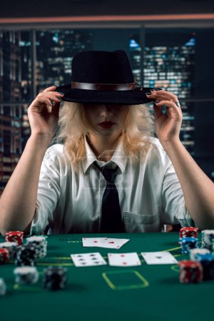 Photo for Attractive girl in shirt and hat playing poker and holding cards in casino. woman player.poker. excitement - Royalty Free Image