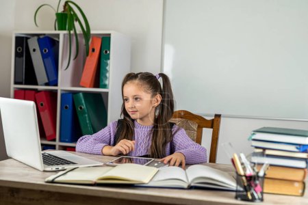 Foto de Retrato de una hermosa chica en el aula en un escritorio con libros y una computadora. el concepto de aprendizaje. la escuela. tiempo escolar - Imagen libre de derechos