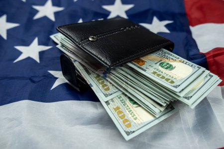 Portefeuille en cuir avec billets de cent dollars isolés sur fond de drapeau des États-Unis. prospérité du pays. symbole de richesse.