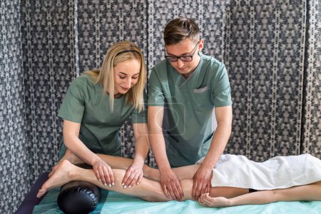 Photo for Two massage therapists a woman and a ma give a double foot and leg massage to a girl in a spa salon. Four hands of masseur during massage close up - Royalty Free Image