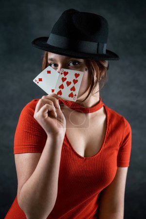 Photo for Young girl in a new dress and hat deals cards at a poker game at a green table. poker game concept. woman - Royalty Free Image