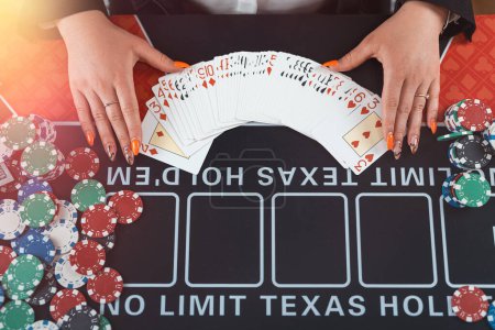 Foto de Manos de croupier femenino están tomando cartas de juego en la mesa de póquer en el casino. Concepto de juego - Imagen libre de derechos