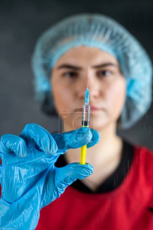 Foto de Enfermera joven caucásica grave o médico sostienen jeringa que prepara a los pacientes la vacunación antibiótico isoalted en negro. Concepto de salud y ciencia - Imagen libre de derechos