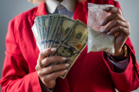 Photo for Woman holding a hundred dollar bill for each dose of cocaine heroin or other drug and drugs in a bag. drugs and dollars. - Royalty Free Image