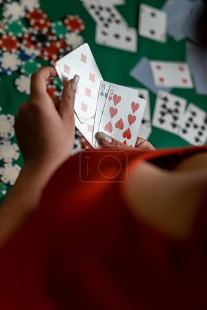 Photo for Young girl in a new dress and hat deals cards at a poker game at a green table. poker game concept. woman - Royalty Free Image