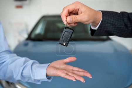 Téléchargez les photos : Vendeur donner voiture client clé après accord de succès au showroom moderne. de près. concept de vente - en image libre de droit