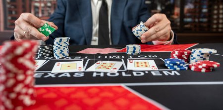 Mann trägt Anzug beim Pokerspielen am Casino-Tisch und gewinnt Royal Flush im Casino. Glücksspielkonzept