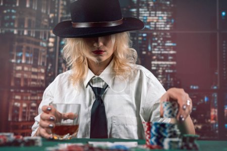 Photo for Attractive girl holding cards and poker chips at casino table hiding her gaze. player girl poker. casino - Royalty Free Image