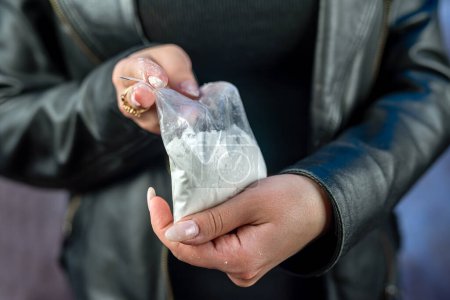 Photo for Closeup of female drug dealer hold cocaine in plastic packet for sale. Criminal illegal concept - Royalty Free Image