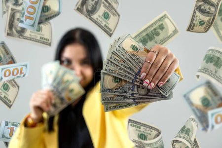 Hübsche kaukasische Frau feiert den Gewinn des großen Geldes und fliegt Dollarscheine aus der Luft. Finanzkonzept