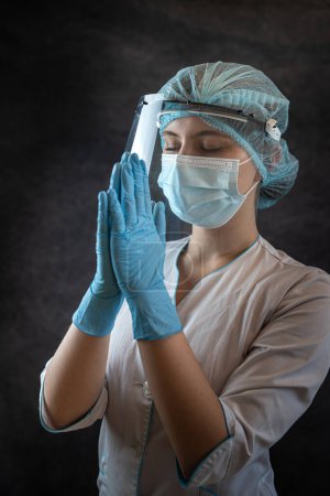 Photo for Portrait woman doctor in uniform closed her eyes, clasped her hands and praying to God. Concept of  faith and hope - Royalty Free Image