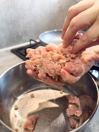 Female hands make meatballs with red fat mince, close up. Raw food