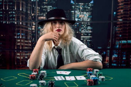 attractive girl in shirt and hat playing poker and holding cards in casino. woman player.poker. excitement