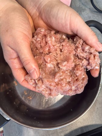 Les mains féminines font des boulettes de viande avec de la graisse rouge hachée, fermer. Produits alimentaires bruts