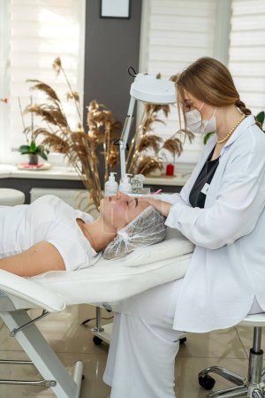 masajista terapeuta femenina haciendo relajarse procedimiento de masaje facial rejuvenecedor al cliente en el salón de spa. Tratamiento de belleza para una piel sana