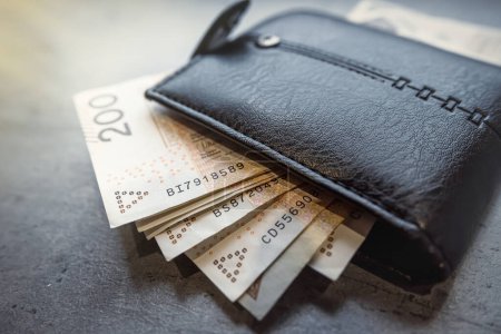 200 billets de 100 zlotys dans un portefeuille masculin noir. Budget domestique et concept d'épargne financière