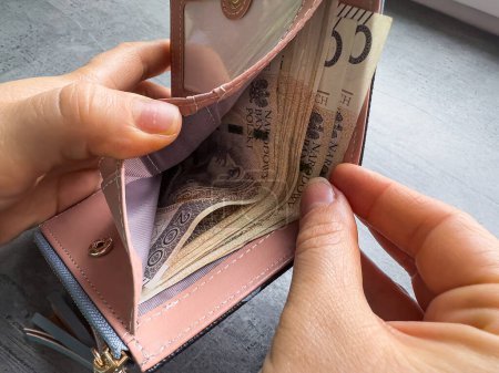 Nahaufnahme Frau zieht polnischen Zloty Geld aus Brieftasche. Polnische Wirtschaft. Frau zählt das Geld