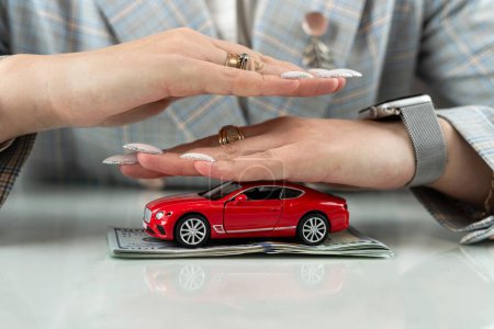 Versicherung oder Schutz des Autos mit Dollargeld und der Hand des Vechicle. Autovermietung oder Verkauf