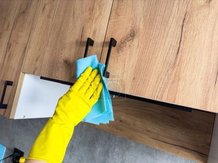 Hausfrau in gelbem Handschuhwaschtisch in der Küche. Sanieren, zu Hause putzen