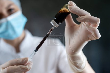Femme caucasienne infirmière ou scientifique en uniforme médical complet préparant le vaccin avec une seringue pour isolée humaine. Vaccin contre la grippe ou le coronavirus