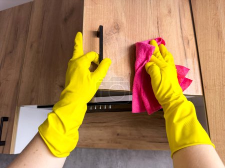 Hausfrau in gelbem Handschuhwaschtisch in der Küche. Sanieren, zu Hause putzen