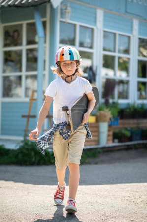 Foto de Full-length portrait of a serious young skateboarder with the board in the hand walking ahead - Imagen libre de derechos