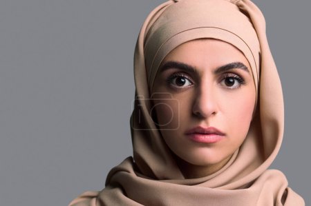 Photo pour Une Arabe. Tête d'une jeune femme en hijab beige - image libre de droit