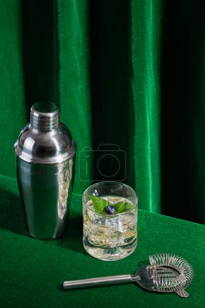 Téléchargez les photos : Boisson alcoolisée avec myrtille et feuille de menthe, avec ustensiles de mixologie sur fond vert pour barman, pas de personnes - en image libre de droit