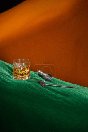 Téléchargez les photos : Boisson alcoolisée avec glace sur un espace abstrait vert et orange avec kit barman, pas de personnes - en image libre de droit
