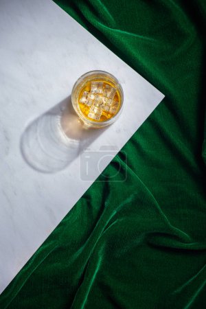 Téléchargez les photos : Liqueur d'orange dans un verre de cristal avec de la glace sur une mosaïque blanche sur le dessus d'une nappe verte, aucun peuple - en image libre de droit