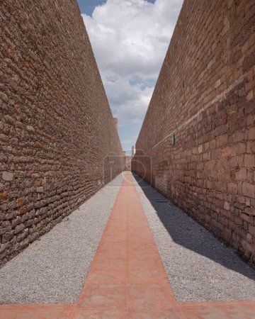 Photo for Prison corridor would expenitentiate. Double stone wall with blue sky and clouds, part of the Leonora Carrington Museum, without people - Royalty Free Image