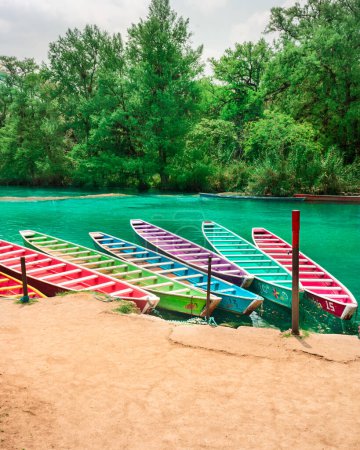 Sechs bunte Holzboote, die am Ufer eines schönen Flusses Huasteca in El Esalto del Meco Mexiko geparkt sind, mit dem tropischen Wald im Hintergrund