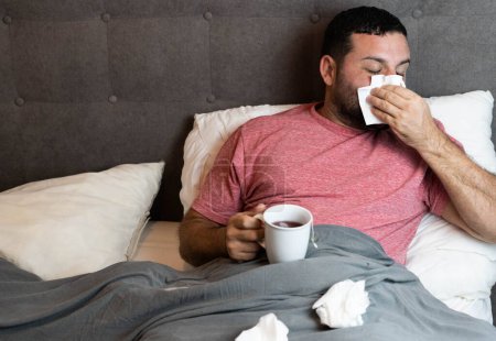 Mann mittleren Alters krank im Bett mit Grippe-Symptomen