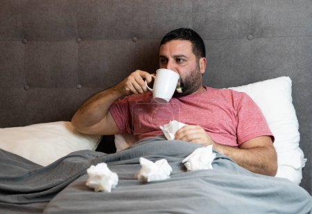 Mann mittleren Alters krank im Bett mit Grippe-Symptomen