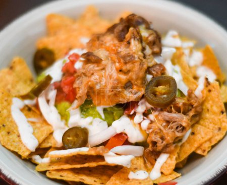 Serving of nachos with meat, cheese, white sauce and jalapenos