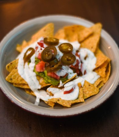 Serving of nachos with white sauce and jalapenos