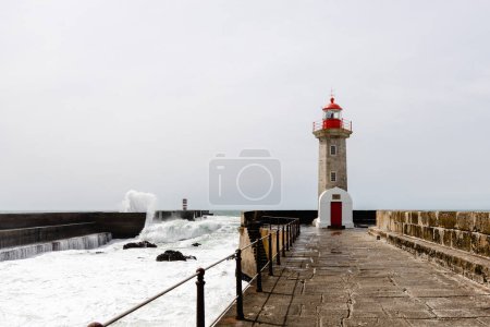 Felgueiras Leuchtturm in Porto an der Atlantikküste mit riesigen Wellen an einem sonnigen Tag, plätschernde Wellen bei Farol de Felgueiras