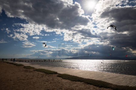 Un montón de kitesurfistas en el mar con nubes dramáticas antes de la lluvia, kitesurfistas en la playa de trabucador en Delta del Ebro