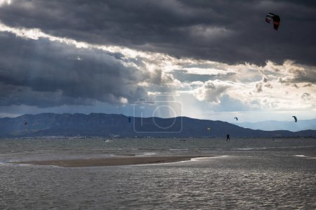 Un montón de kitesurfistas en el mar con nubes dramáticas antes de la lluvia, kitesurfistas en la playa de trabucador en Delta del Ebro