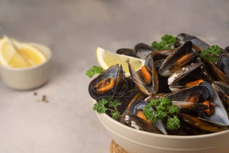 Delicious seafood mussels with with sauce and parsley. Lemon slices and glass of white wine. Clams in the shells. Fresh seafood.