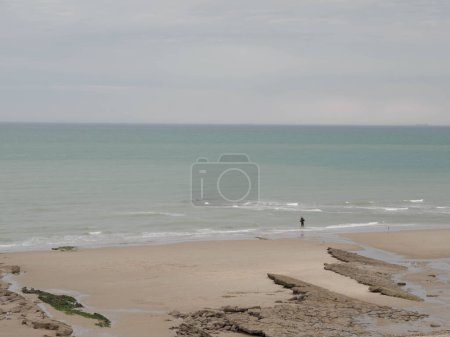 Photo for The sea coast between Audresselles and Ambleteuse. Angler catching sea fish. Waters of the English Channel - The La Manche Channel. France. - Royalty Free Image