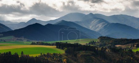 Photo for Mountain landscape. In the foreground, a farmland and autumn trees. In the distance you can see the Low Tatras Zilina Region. Beszeniowa. Slovakia. - Royalty Free Image