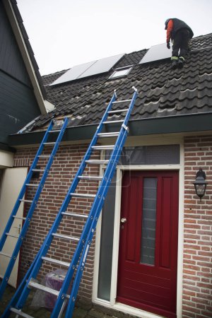 Foto de Trabajador instalación de paneles solares en el techo - Imagen libre de derechos