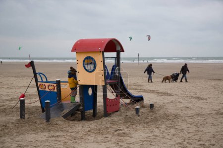 Téléchargez les photos : Aire de jeux pour enfants sur la plage de la mer par temps froid - en image libre de droit