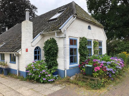 Téléchargez les photos : Belle maison hollandaise avec fleurs dans le jardin - en image libre de droit