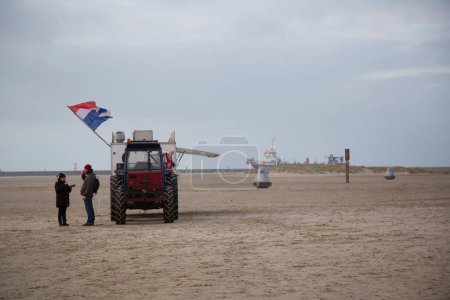 Téléchargez les photos : Tracteur avec remorque de restauration rapide sur la plage de la mer par temps froid - en image libre de droit
