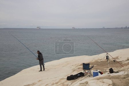 Téléchargez les photos : Homme pêchant sur la côte rocheuse de la mer - en image libre de droit