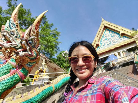 Foto de A young tourtist taking selfie from the entrance to Wat Khao Rang a buddhist Thai temple on the island of Phuket, Thailand. - Imagen libre de derechos