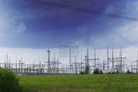 Téléchargez les photos : Poteaux électriques sur le fond d'un ciel bleu foncé, situé au milieu d'un champ d'herbe verte. Photo de haute qualité - en image libre de droit