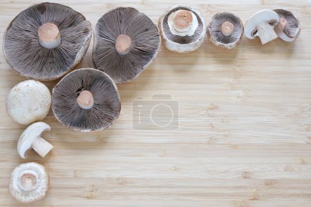 Téléchargez les photos : Des champignons Agaricus entiers et coupés se trouvent sur la table. Champignons de différentes tailles. Contexte. Un endroit pour votre texte. Photo de haute qualité - en image libre de droit